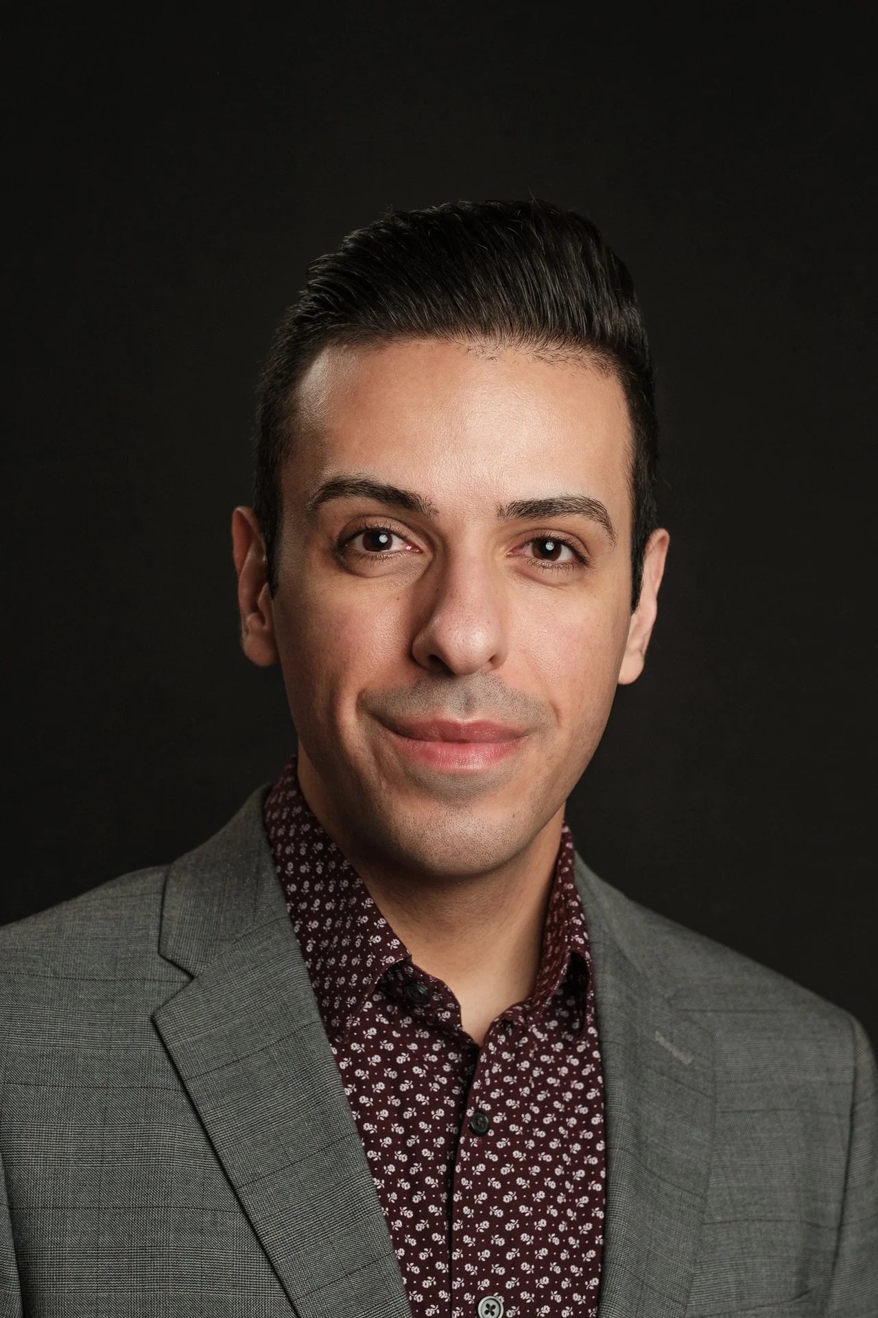 Studio headshot in a grey suit