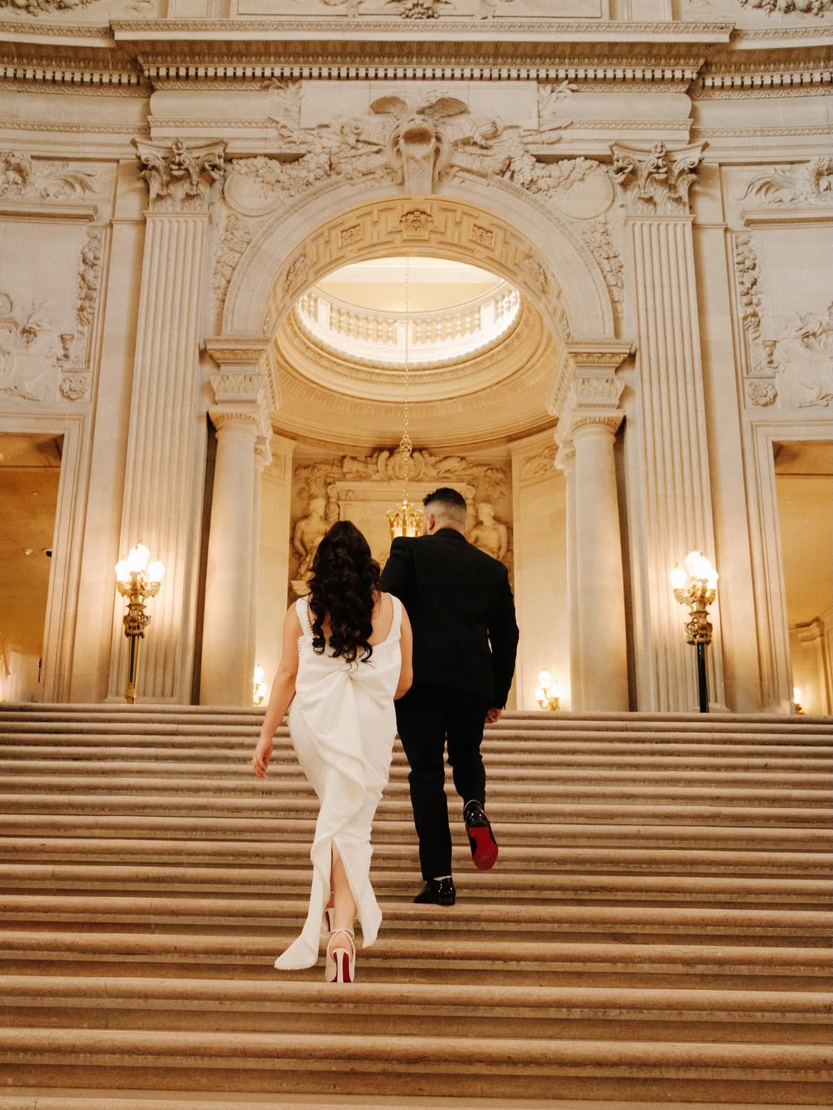 Renita and Jason walking up the City Hall stairs — couple photography by Steven Lelham in San Francisco City Hall
